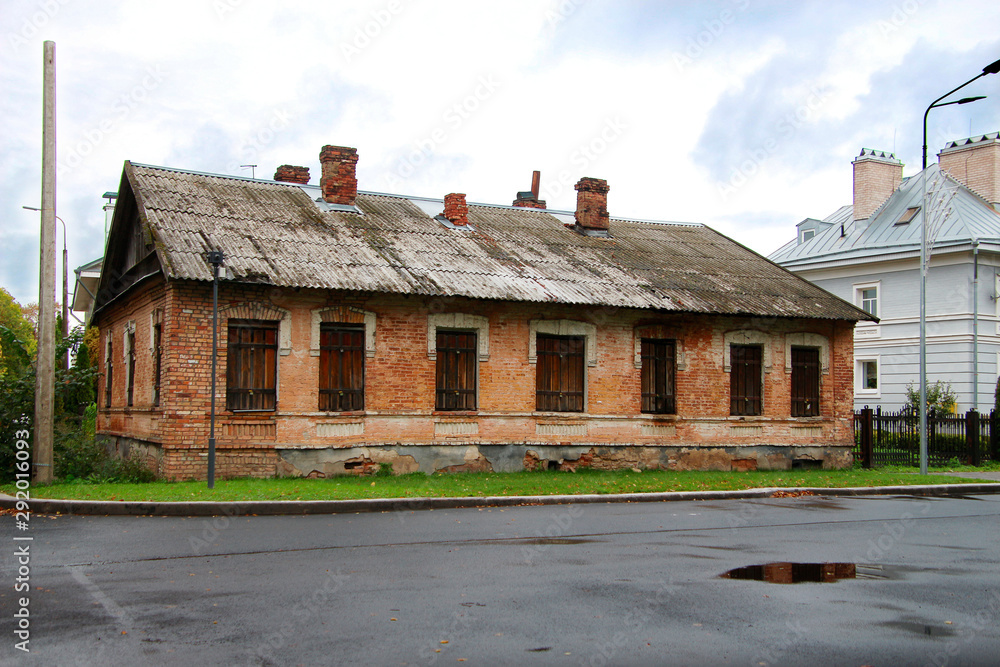 old brick house on the street with shuttered windows and roof pipes old brick house on the street with shuttered windows and roof pipes