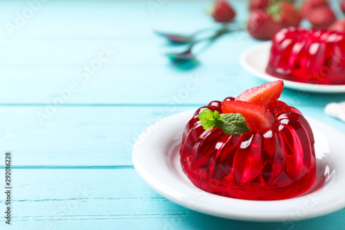 Delicious red jelly with strawberry and mint on light blue wooden table. Space for text photo