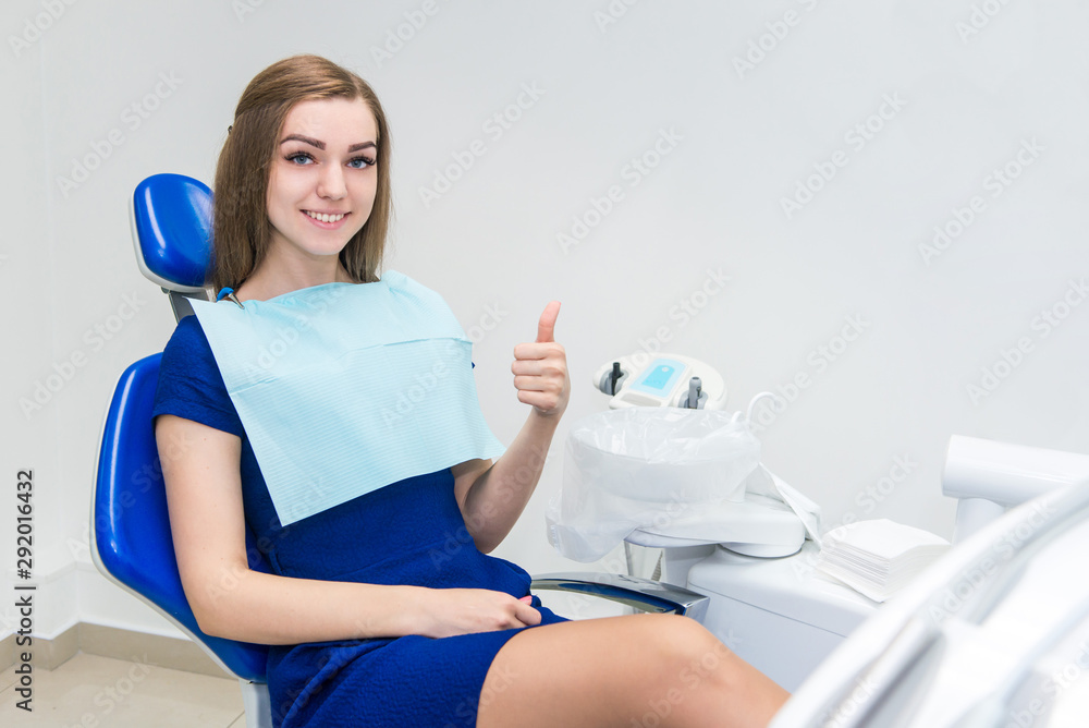 Young girl patient smiles and shows thumb up in the doctor’s chair in the dental office Young girl patient smiles and shows thumb up in the doctor’s chair in the dental office