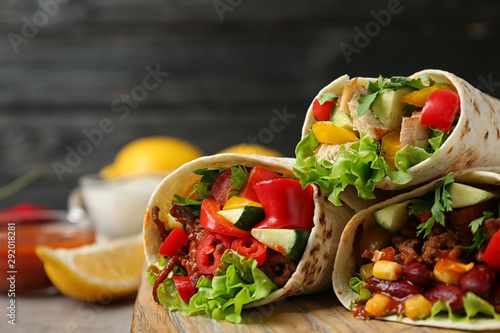Εκτύπωση καμβά Board with delicious meat tortilla wraps on light table against black background