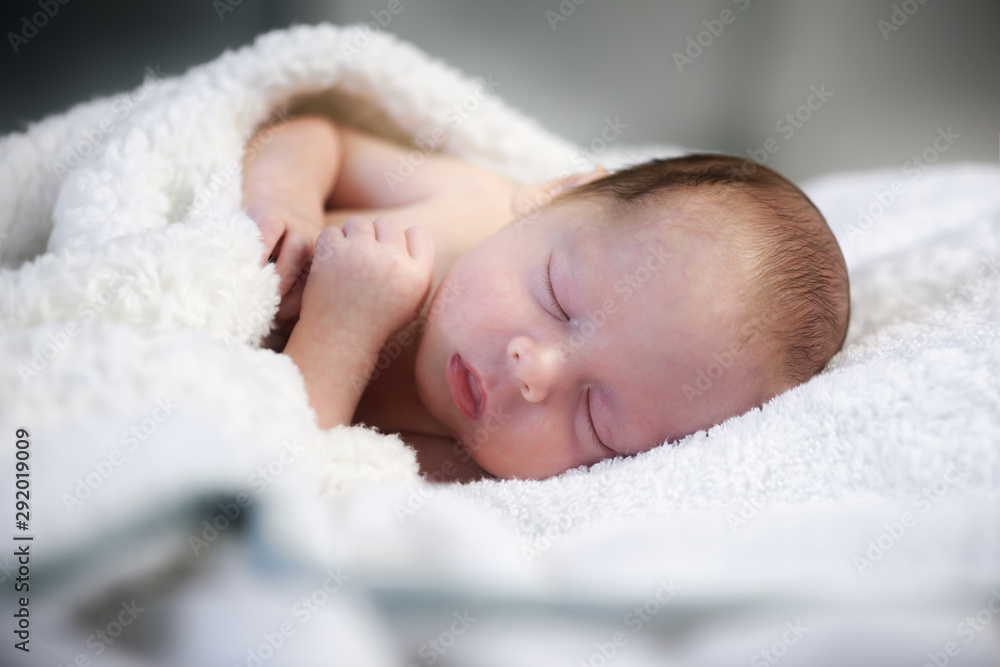 Sleeping newborn baby under soft white carpet. New life concept Sleeping newborn baby under soft white carpet. New life concept
