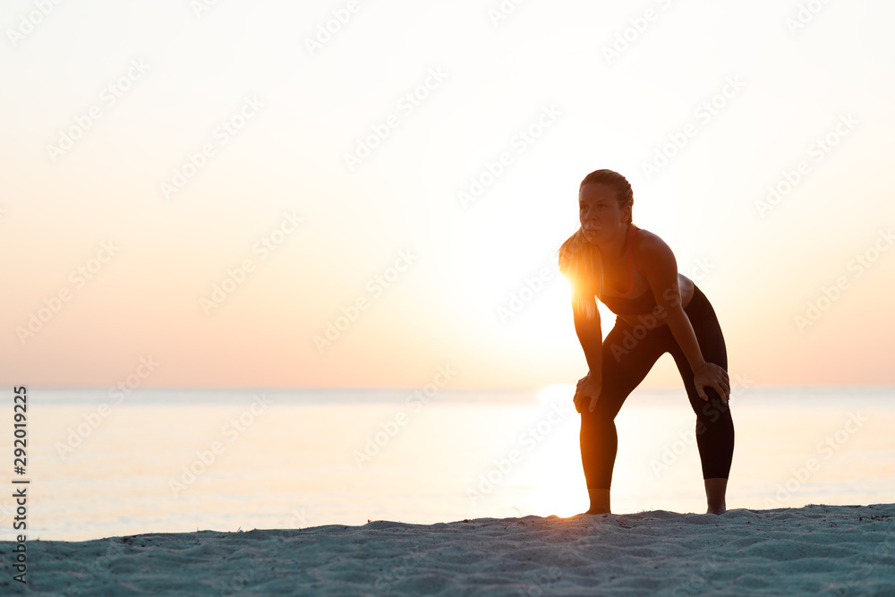 Young woman catching a breath after a run on the beach