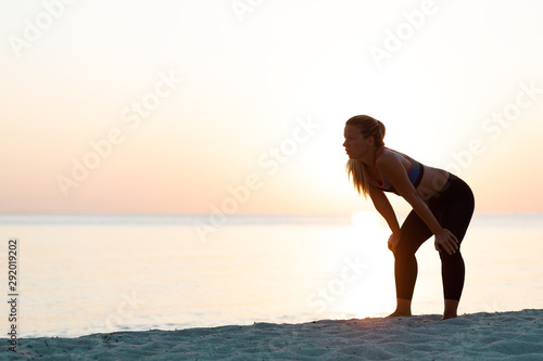 Young woman catching a breath after a run on the beach