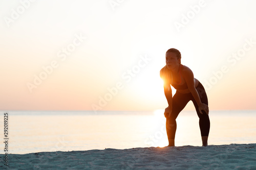 Fototapeta Naklejka Na Ścianę i Meble -  Young woman catching a breath after a run on the beach
