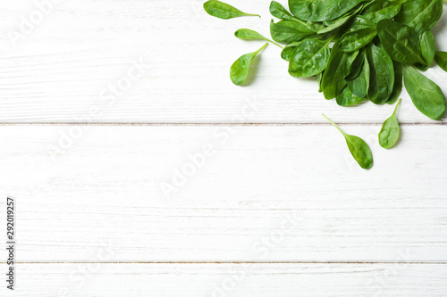 Heap of fresh green healthy spinach on white wooden table, top view. Space for text © New Africa