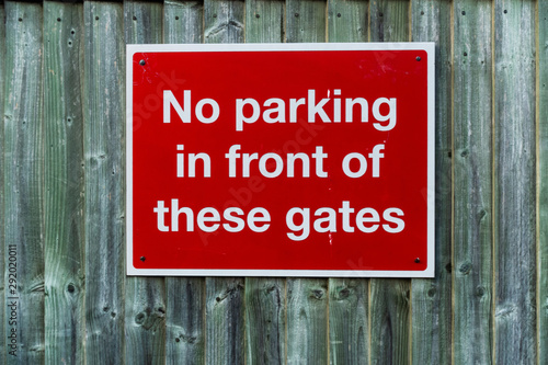 A no parking sign attached to a wooden gate