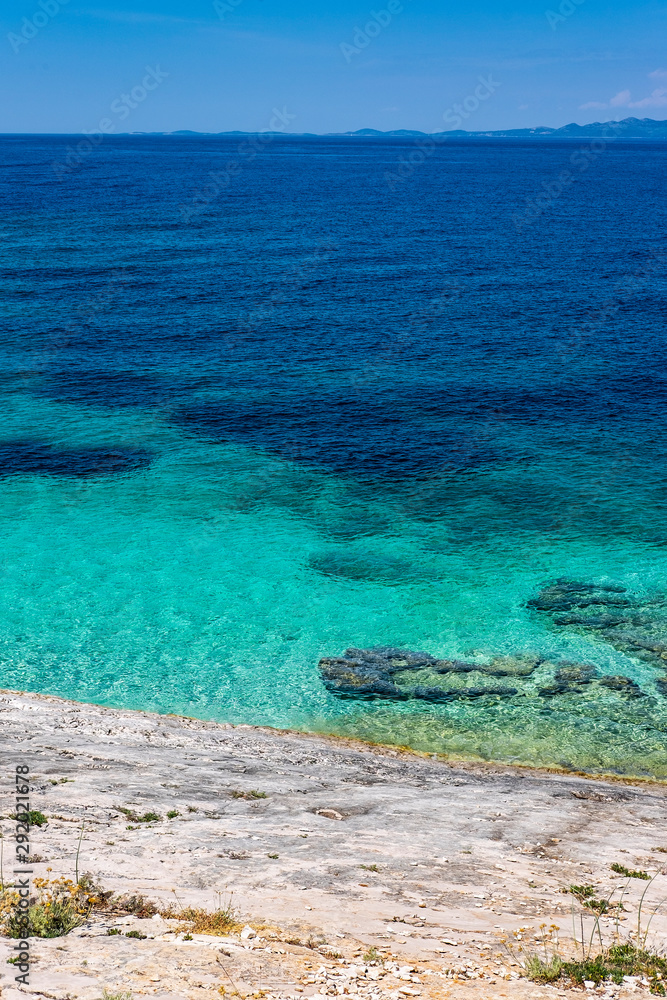 Stone beach on Proizd Island near Korcula Island, Dalmatia, Croatia, blue lagoon, clear sea water and blue sky, popular tourist destination  