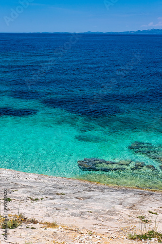 Stone beach on Proizd Island near Korcula Island, Dalmatia, Croatia, blue lagoon, clear sea water and blue sky, popular tourist destination 