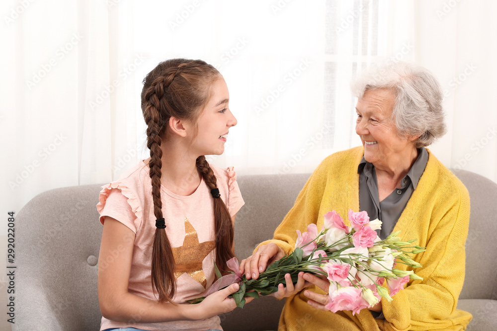 Cute girl congratulating her grandmother in living room Cute girl congratulating her grandmother in living room