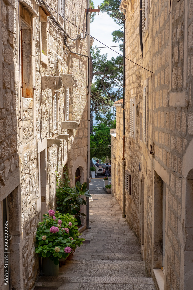 Famous narrow stone street with stone houses and facades and flowers in historic fortified Korcula town, Korcula Island, Dalmatia, Croatia