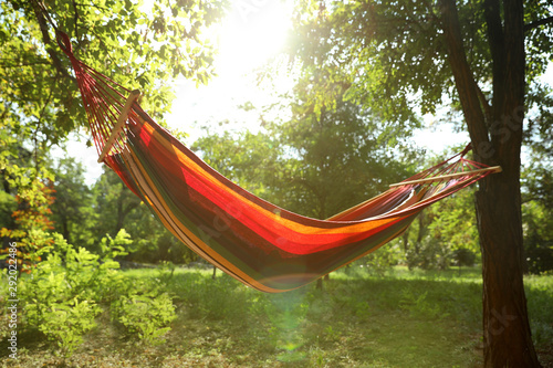 Woman resting in comfortable hammock at green garden