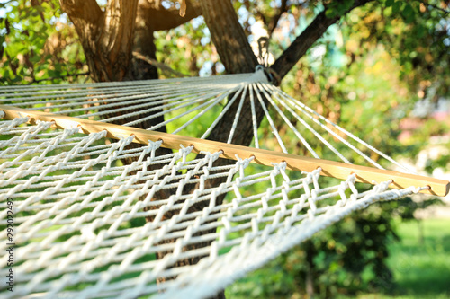 Comfortable net hammock hanging in green garden, closeup