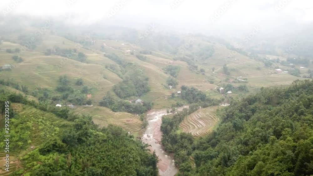 Aerial view of mountains full of rice fields and a river on a foggy day in Sa Pa, Vietnam. Aerial view of mountains full of rice fields and a river on a foggy day in Sa Pa, Vietnam.