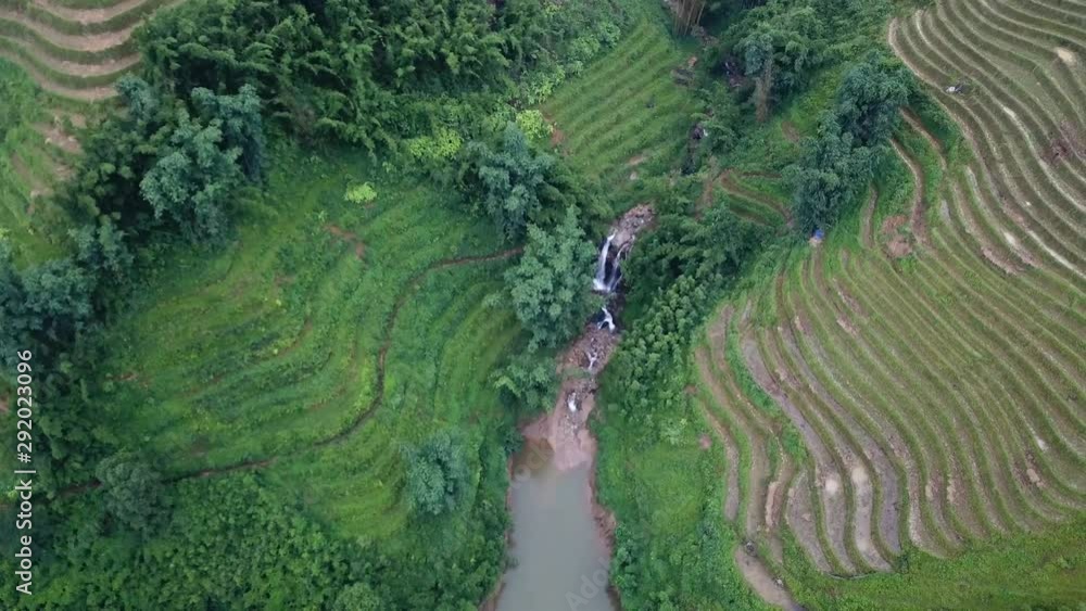 Aerial view of a waterfall surrounded by rice field terraces in Sa Pa, Vietnam. Aerial view of a waterfall surrounded by rice field terraces in Sa Pa, Vietnam.
