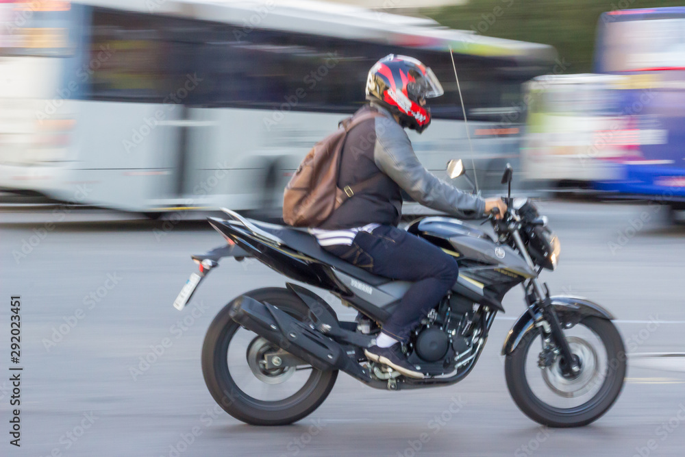 Fototapeta premium Panning picture of a motorcycle man crossing the streets. Blurred movement effect. Rio de Janeiro, Brazil. 2017