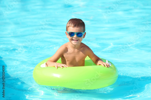 Happy little boy with inflatable ring in swimming pool