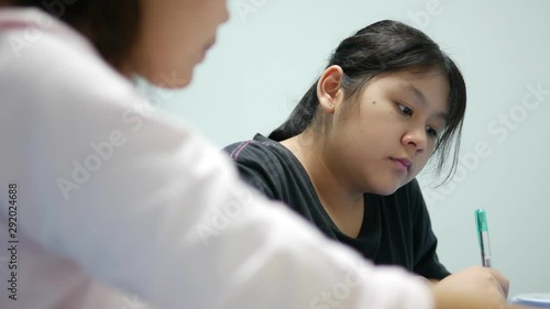 Asian high school student girl is studying in classroom while her teacher is teaching.