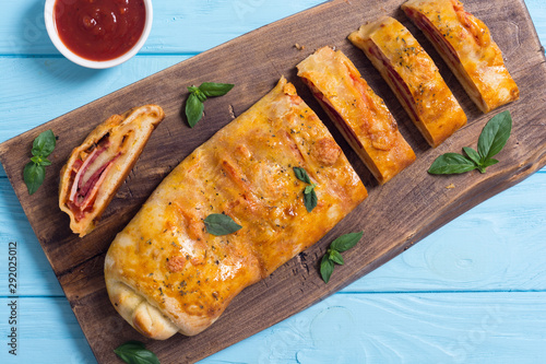 Pizza roll stromboli with cheese salami olives and tomatoes