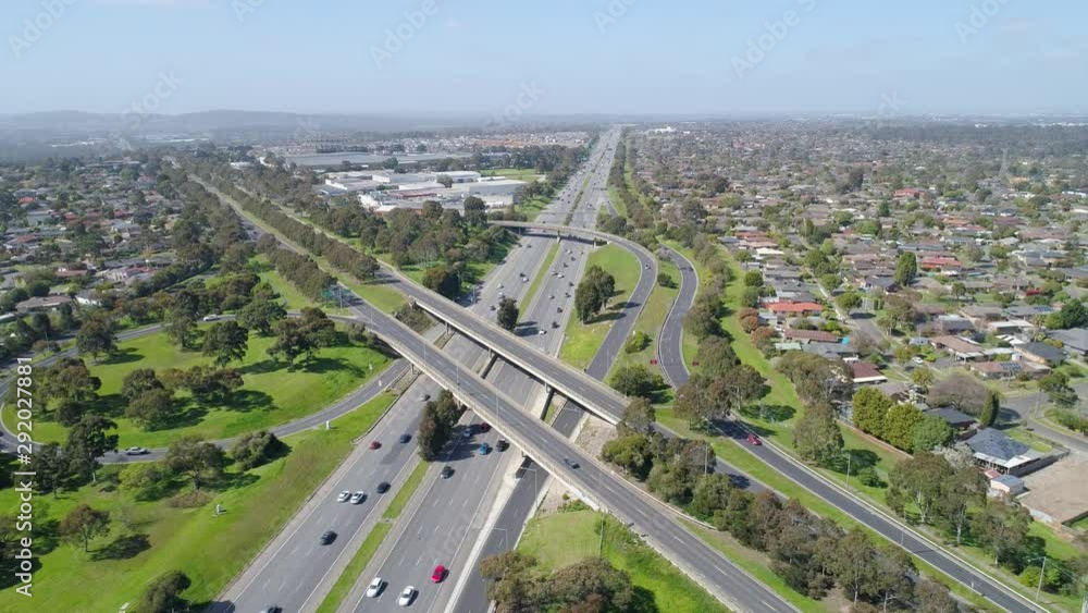 Backwards flight away from modern highway interchange and driving cars on bright sunny day Backwards flight away from modern highway interchange and driving cars on bright sunny day