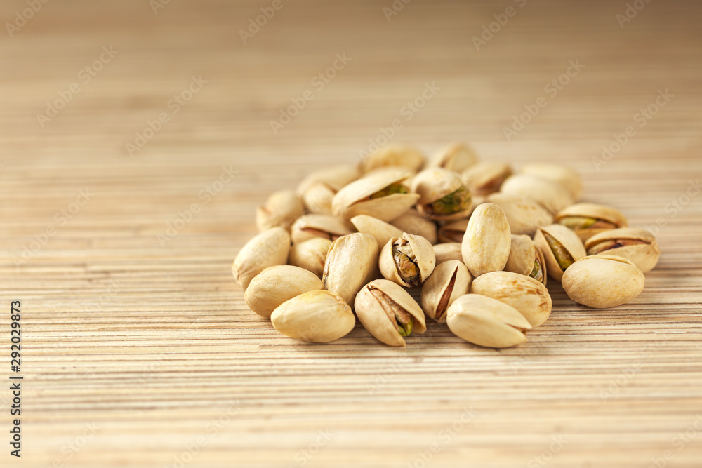 Heap of pistachios on wooden background, close up with copy space Heap of pistachios on wooden background, close up with copy space