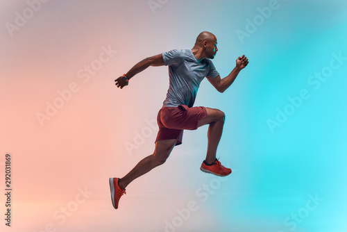 New champion. Full length of young african man in sports clothing jumping against colorful background