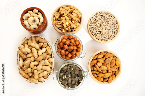 Containers filled with different types of nuts and seeds on a white background