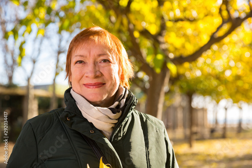 Happy elderly woman with a bouquet of maple leaves in autumn park photo