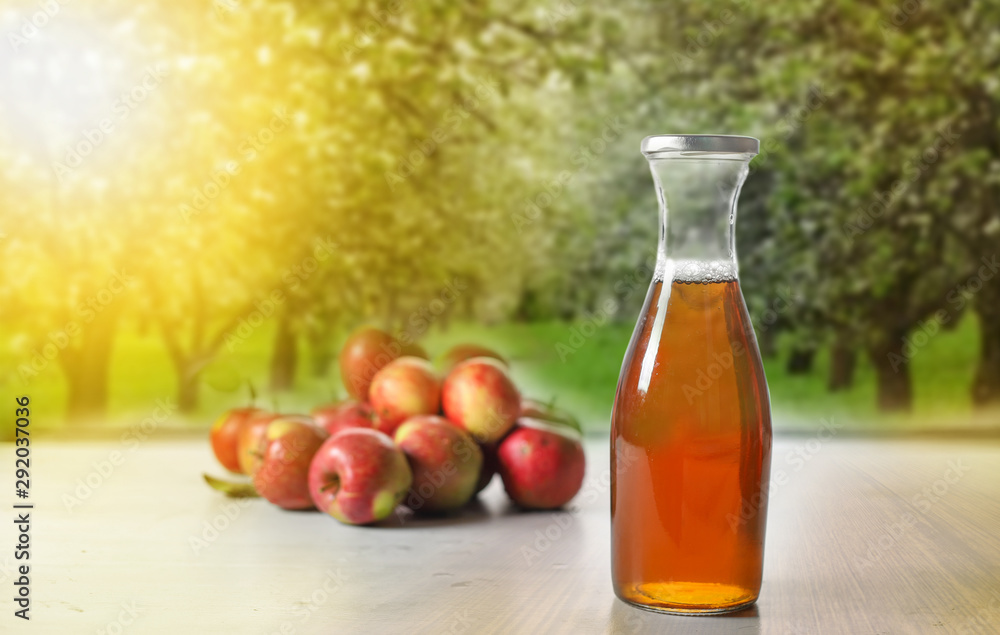apple juice in glass bottle and apples on Woden Provence table on natural background apple juice in glass bottle and apples on Woden Provence table on natural background
