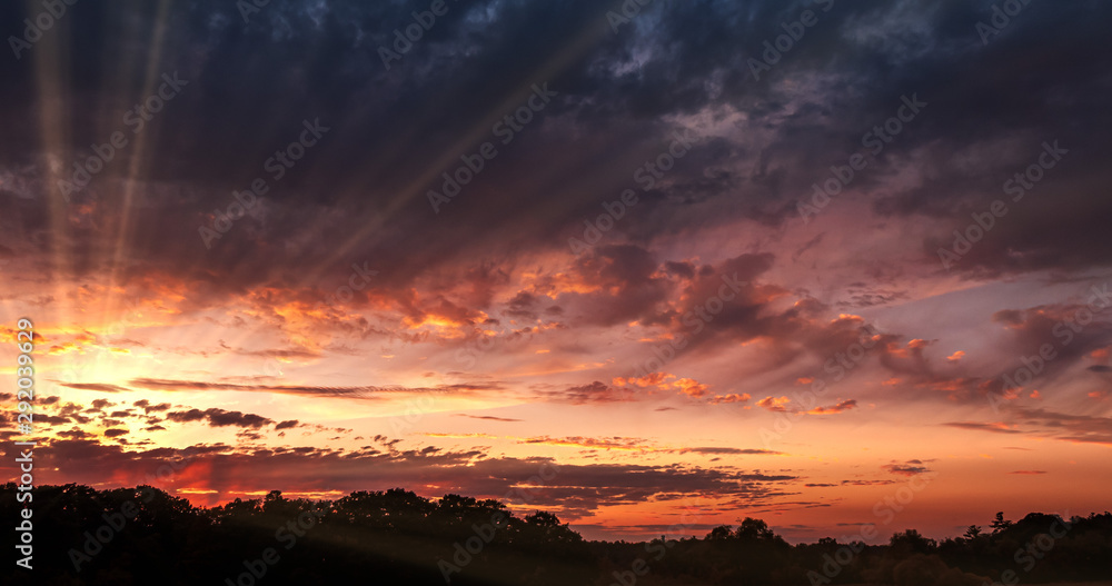Dramatic Sunset over Storm Clouds. Evening, Large beautiful orange color sunset sky. Red purple orange blue pink. Landscape of Storm clouds moving across the sky against the setting sun.