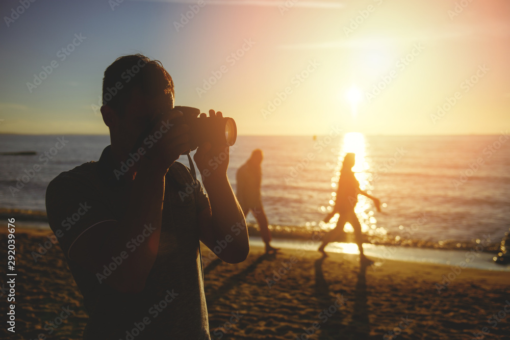 Silhouette of young photographer on the beach
