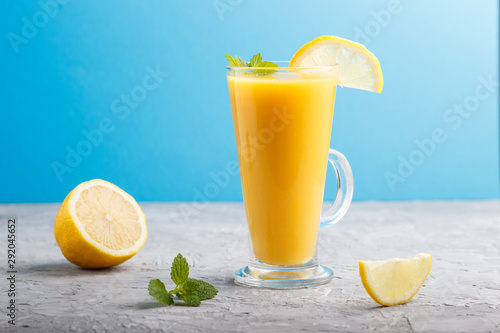 Glass of lemon drink on a gray and blue background. Side view