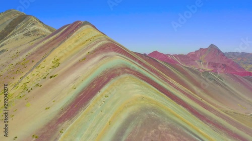 Aerial landscape of hiking scene at Rainbow Mountain at  Vinicunca Valley. Apu Ausangate is behind. All rocks, mountains and sand is invaded by red colors. Cusco Region, Peru