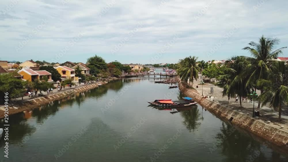 Aerial shot over the river in Hoi An with many tourists walking in the riverside. Aerial shot over the river in Hoi An with many tourists walking in the riverside.