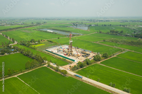 Oil and gas land drilling rig onshore in the middle of a rice field aerial view from a drone