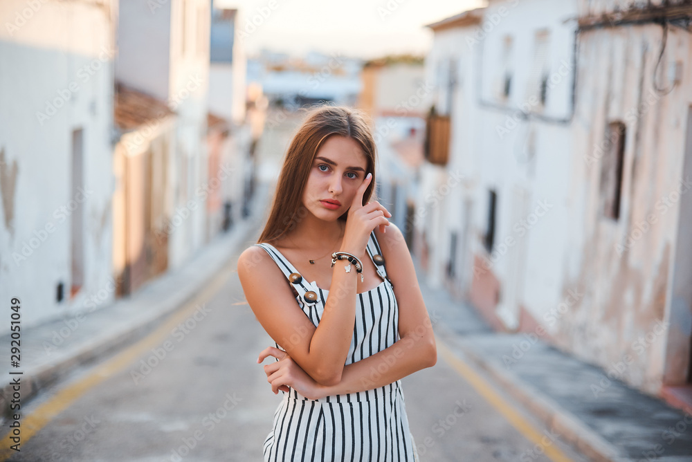 Fashion portrait of young elegant woman walking on old the narrow streets.