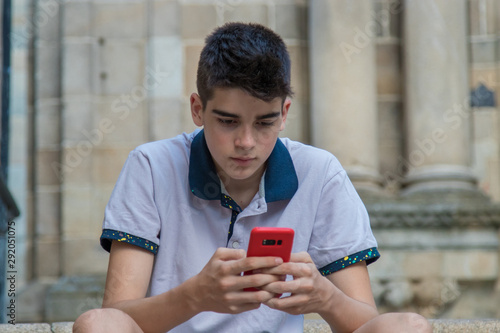 young teenage man with mobile phone outdoors photo