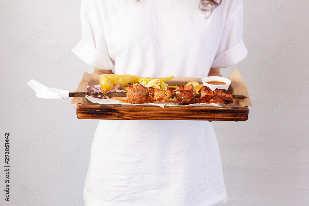 Waitress is holding a tray with party snacks: grilled chicken, potato crisp, coleslaw and vegetables