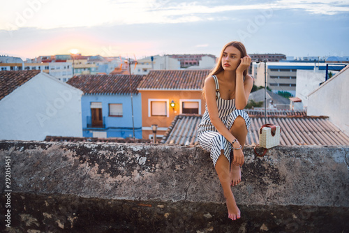 Young elegant barefoot woman posing on the street at sunset.