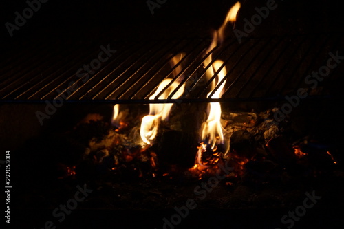 Une grille, des flammes et des braises