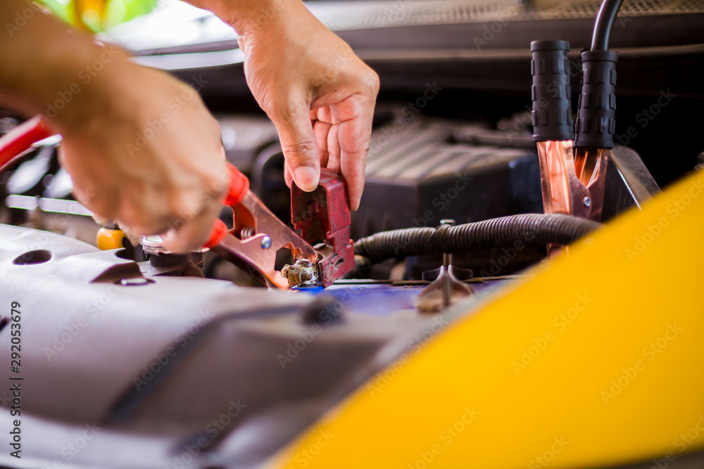selective focus charging yellow car with electricity trough cables. first connect anode then follow connect negative connector battery selective focus charging yellow car with electricity trough cables. first connect anode then follow connect negative connector battery