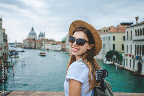 Happy smiling tourist girl posing on a bridge in front of Grand Canal and Basilica Santa Maria della Salute in Venice