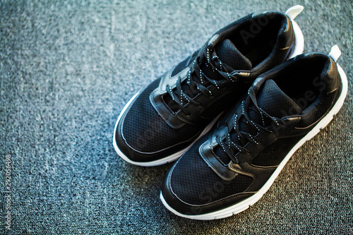 Pair of new stylish black sneakers on floor at home