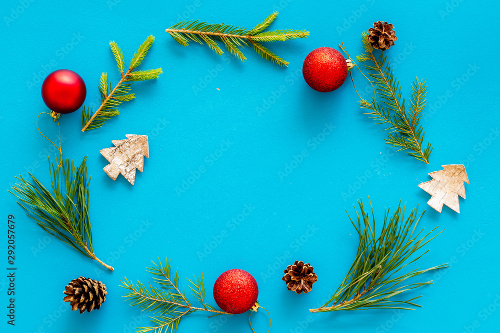 New Year decorative mockup. Fir branches and festive toys frame on blue background top view copy space New Year decorative mockup. Fir branches and festive toys frame on blue background top view copy space