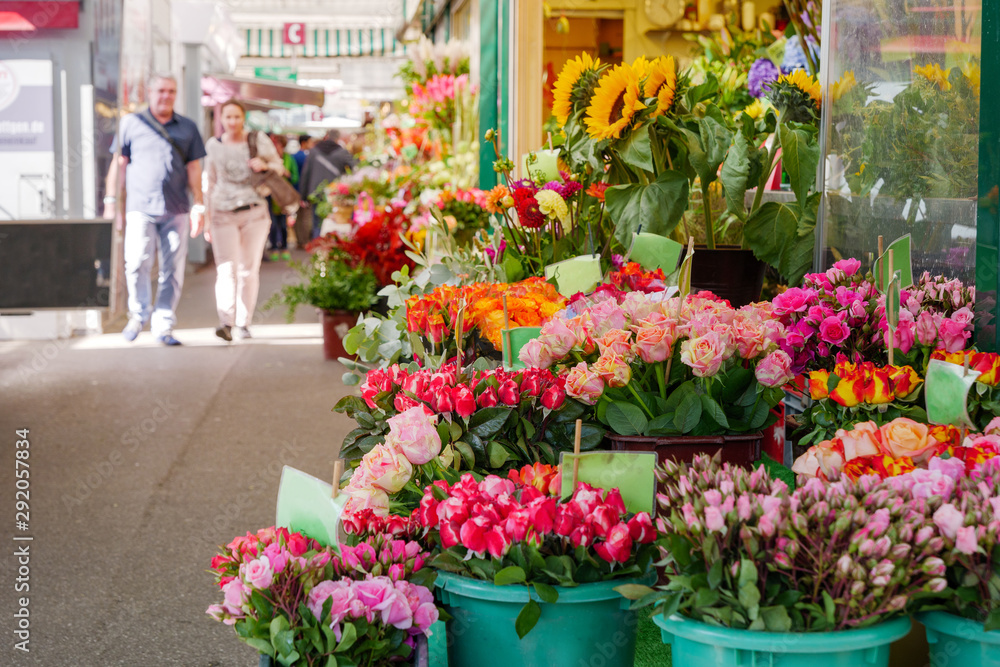 View of colourful various flowers in plastic box are sold at corridor in front of flower stall or floral shop is located in outdoor market in Europe. Typical atmosphere of flower store.   