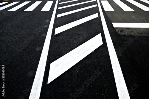 Abstract perspective section of white reflective paint road signage on black asphalt road.