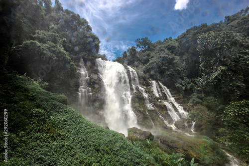 Natural blurred background of waterfalls  fast-flowing currents and water droplets from the wind blowing among the rocks and surrounded by big trees  spontaneous beauty