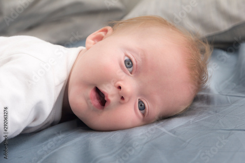 Portrait of cute smiling baby lying on the bed at home