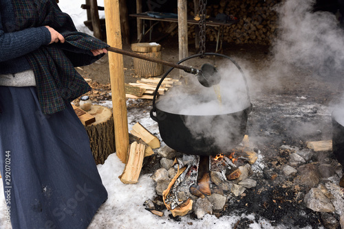 Εκτύπωση καμβά Woman in pioneer garb ladling evaporating sap in cast iron pot to produce maple