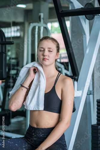 Sports tired woman after exercise wipes sweat on face in fitness gym sport club