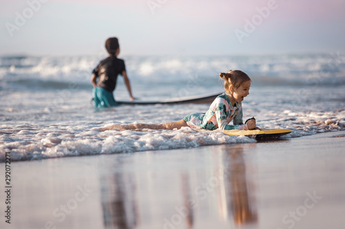 Canvas Print Happy baby girl - young surfer ride on surfboard with fun on sea waves